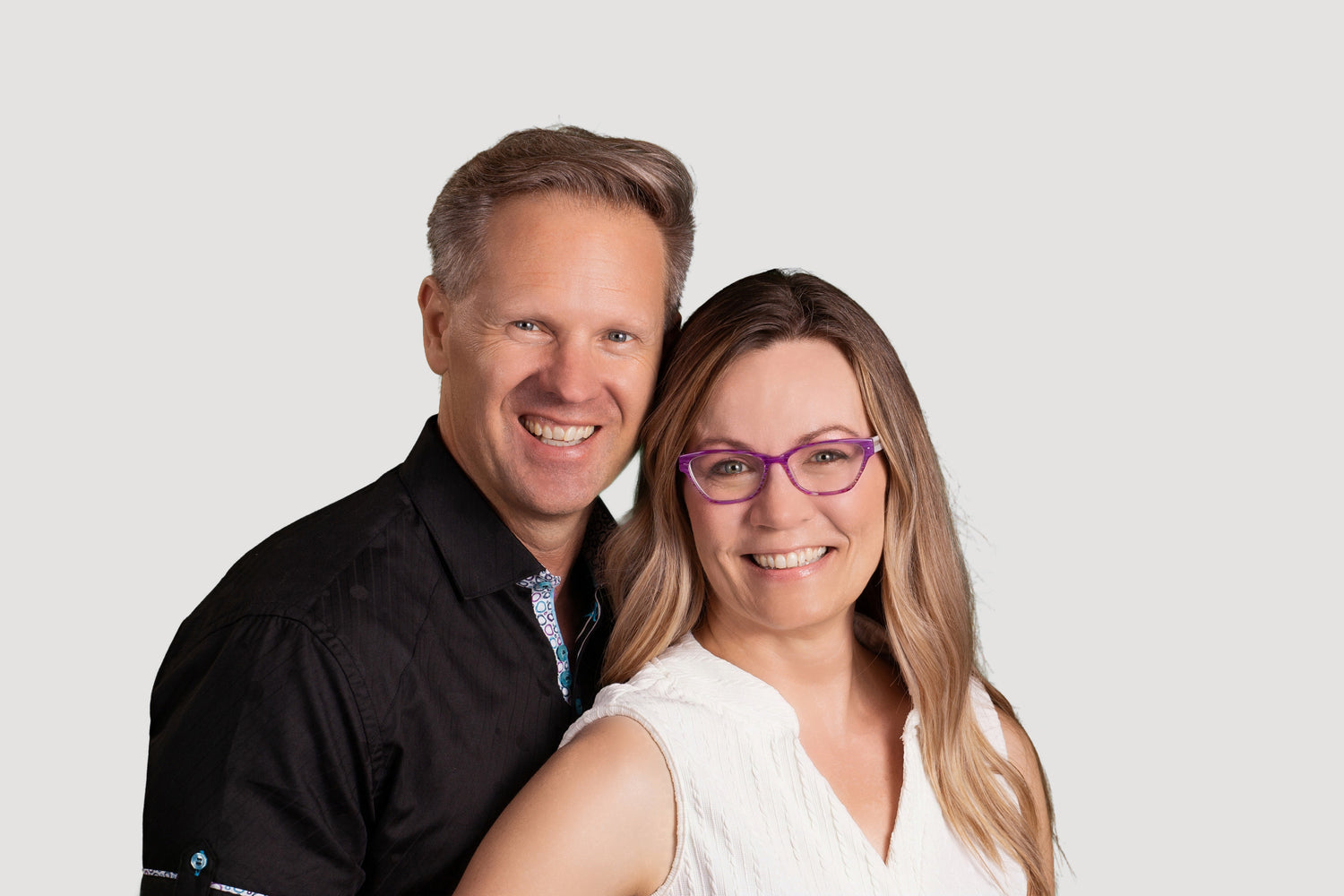 Man and woman standing close together against a plain background